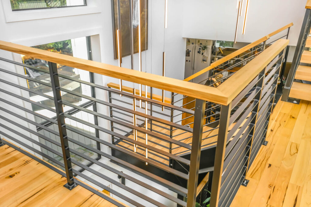 Scala interna con gradini in legno, completata da una moderna ringhiera e parapetto in ferro realizzati artigianalmente da 2A Carpenteria in Ferro