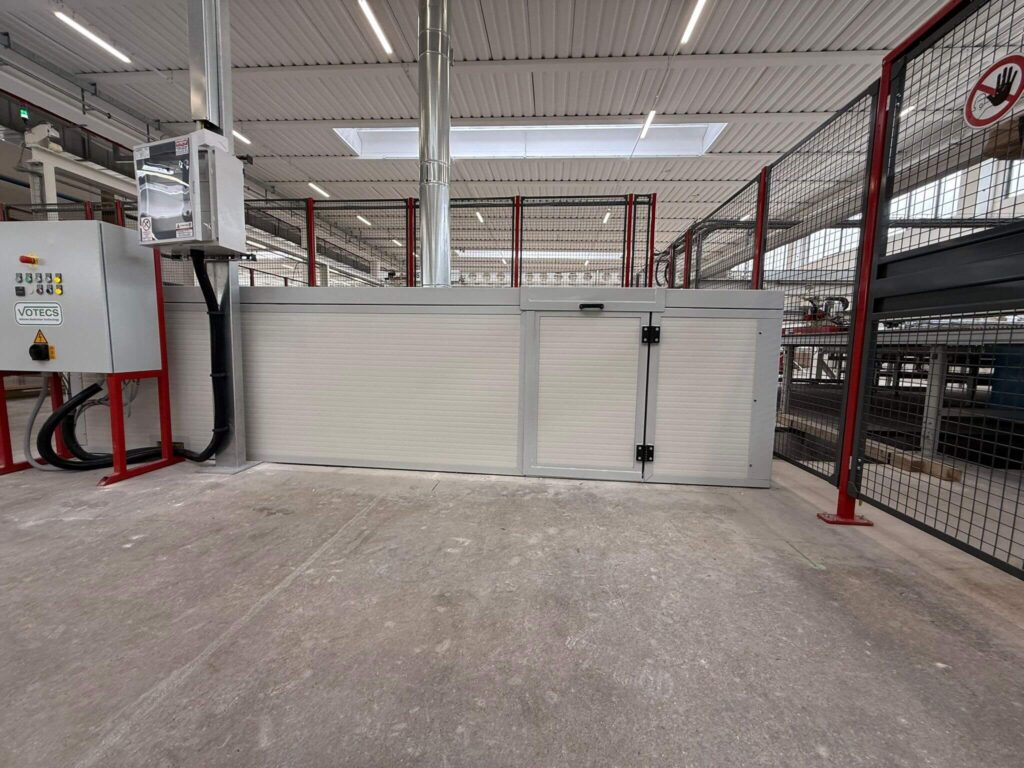 Cabina metallica di protezione per impianti industriali mostrata con gli sportelli di accesso e ispezione aperti. Progettazione, realizzazione e posa a cura di Carpenteria 2A, operativa in tutto il Veneto. - Vista 2