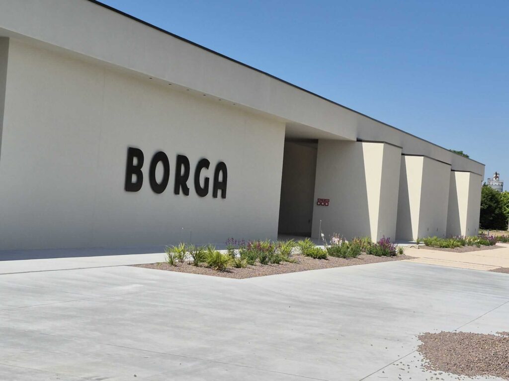 Insegna aziendale esterna in metallo scuro con lettere in rilievo "BORGA", installata sulla facciata di un moderno edificio commerciale. Lavorazione architettonica su misura di Carpenteria 2A, Treviso.