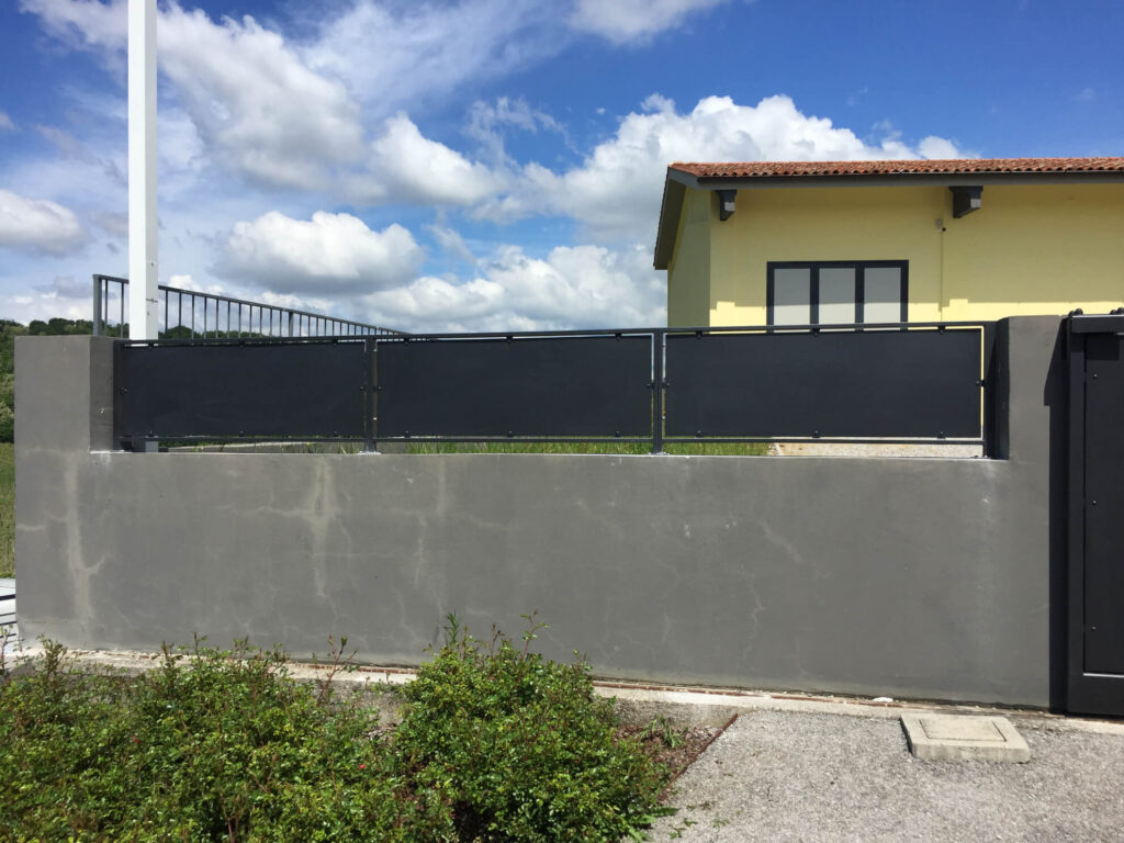 Recinzione di confine moderna realizzata con pannelli ciechi in lamiera metallica scura montati su muretto, progettata per garantire la massima privacy. Installazione di Carpenteria 2A in Veneto.