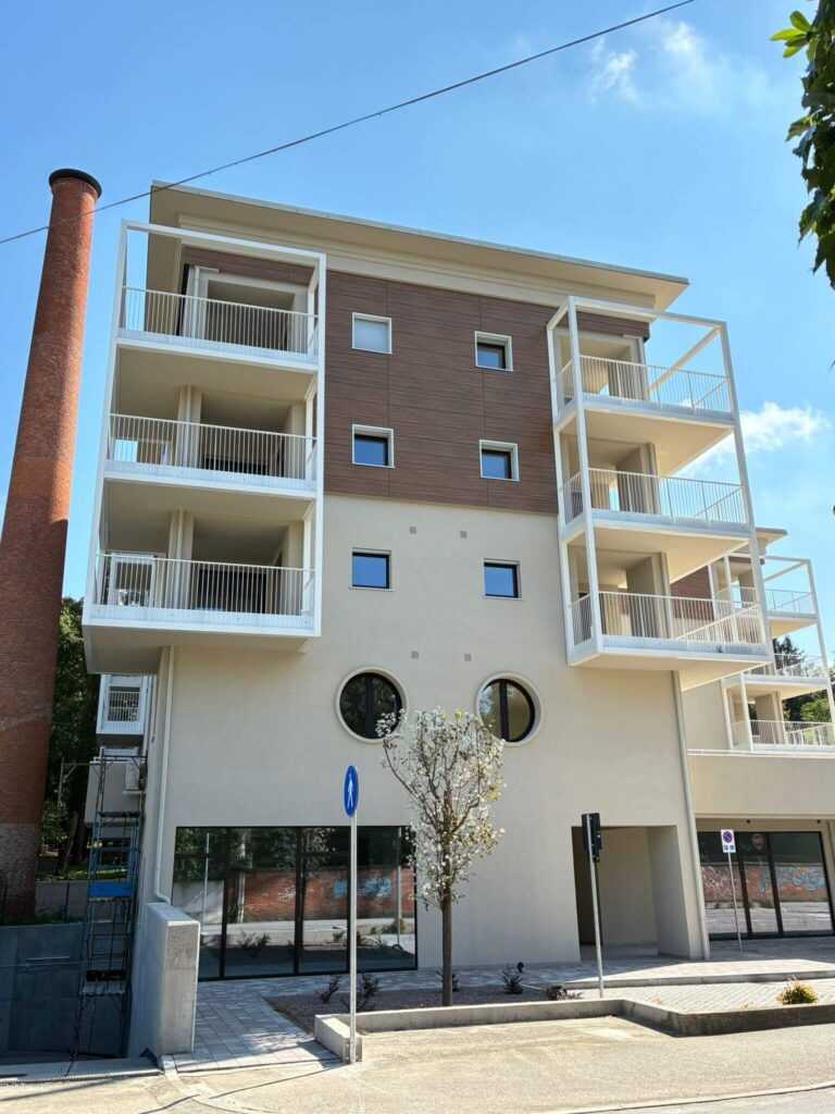 Strutture metalliche per ampi balconi e parapetti verniciati di bianco dal design lineare, installati sulla facciata di un moderno complesso residenziale. Opera di carpenteria per l'edilizia civile di Carpenteria 2A, operante in Veneto.