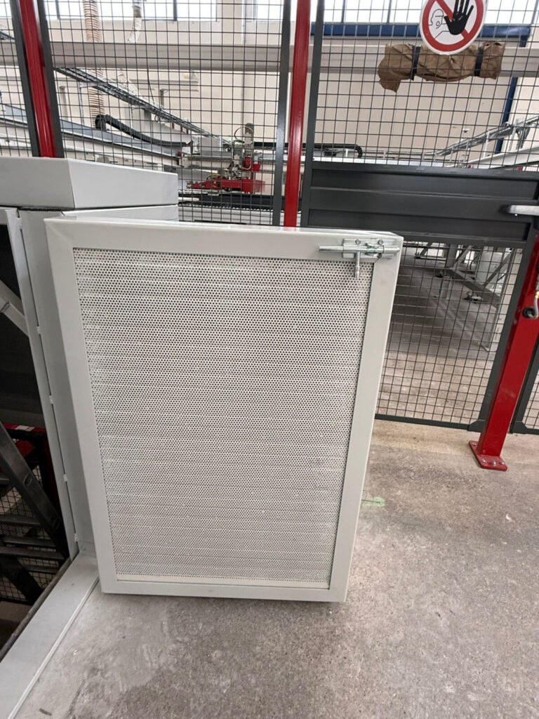Dettaglio di uno sportello di ispezione con rete metallica forata, parte di un carter di protezione per macchinari industriali realizzato da Carpenteria 2A in Veneto - Realizzazioni componenti metallici